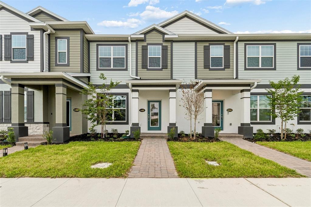 A row of modern two-story townhomes features light-colored siding, stone accents, and paved walkways — 1402 MOUNT ROYAL DRIVE, ST CLOUD, FL