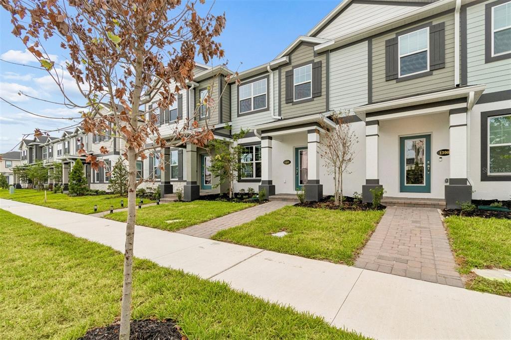 A row of modern townhomes with white stucco, gray siding, and paved walkways — 1402 MOUNT ROYAL DRIVE, ST CLOUD, FL