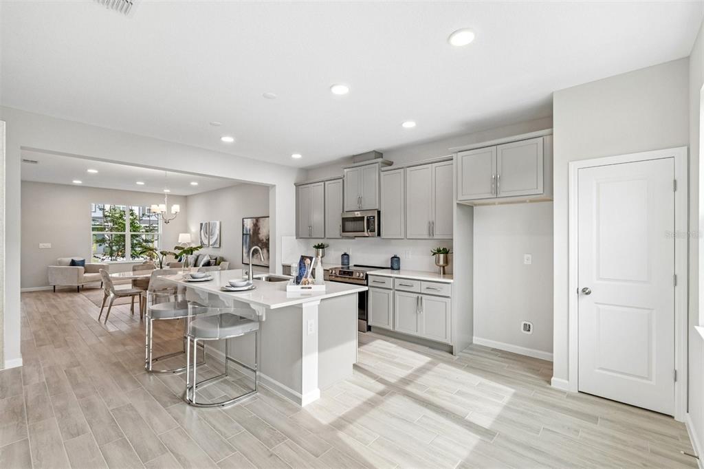 A modern kitchen with gray cabinets, a white island, and light wood-look tile flooring — 1402 MOUNT ROYAL DRIVE, ST CLOUD, FL