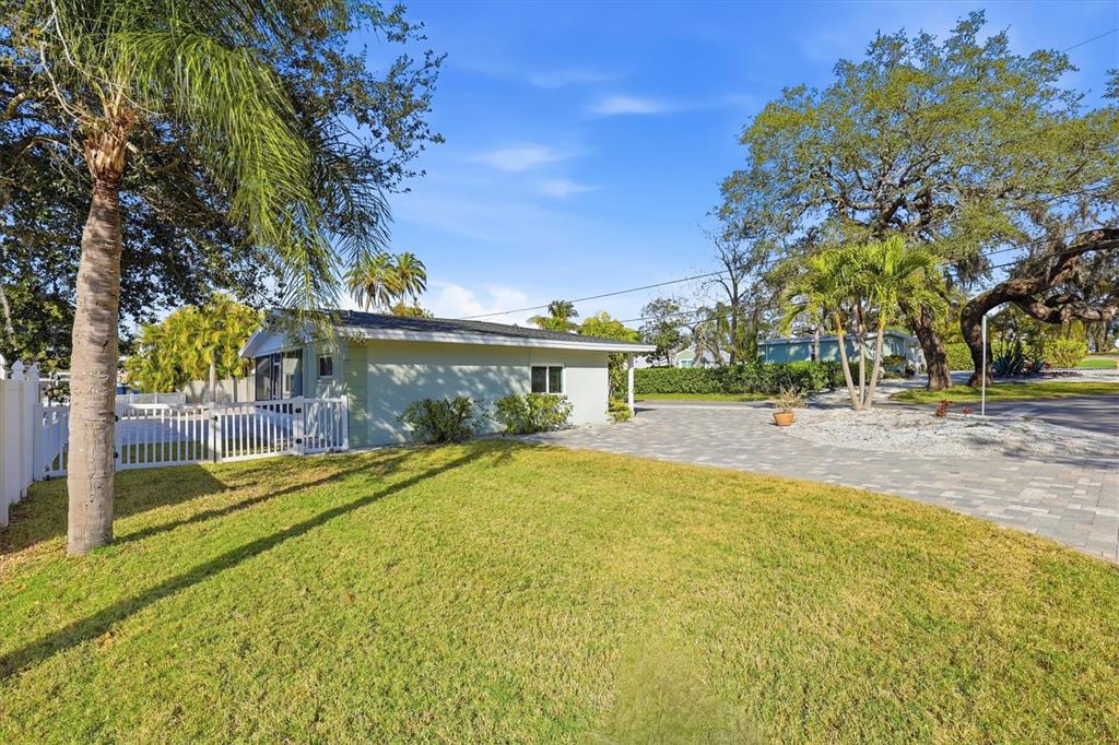 A light green house with a paved driveway and a white fence sits on a lawn — 302 GEORGIA AVENUE, CRYSTAL BEACH, FL