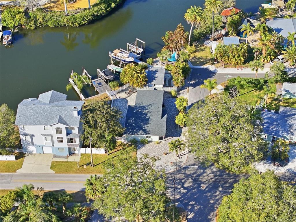An aerial view shows a waterfront house with a boat dock and paved driveway — 302 GEORGIA AVENUE, CRYSTAL BEACH, FL