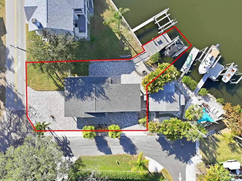 An aerial view shows a waterfront house with a paved driveway, dock, and boat lift — 302 GEORGIA AVENUE, CRYSTAL BEACH, FL