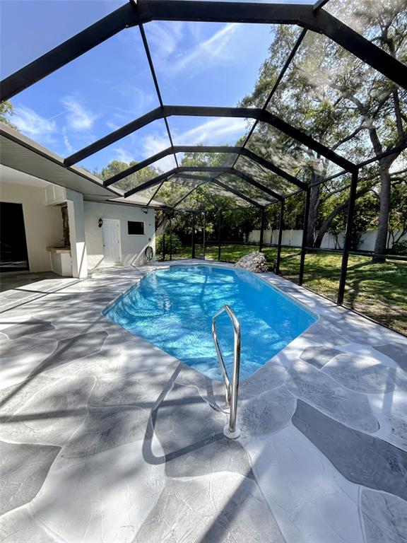 A covered patio features wicker furniture, a stone accent wall, and a swimming pool — 18608 AUTUMN LAKE BOULEVARD, HUDSON, FL