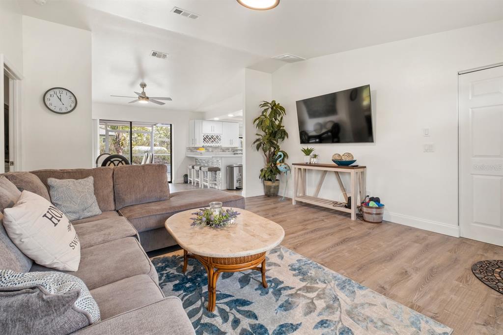 A living room features a sectional sofa, a coffee table, and a wall-mounted television — 9080 CALOOSA DRIVE, VENICE, FL