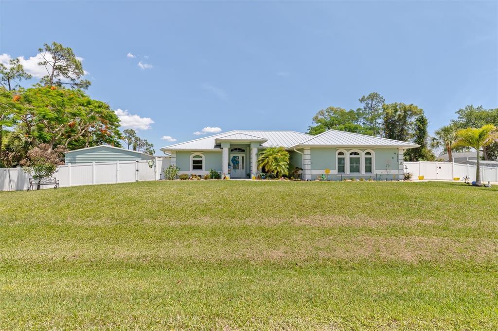 A light green single-story house with a metal roof sits behind a large grassy lawn — 1636 GLENAN ROAD, NORTH PORT, FL