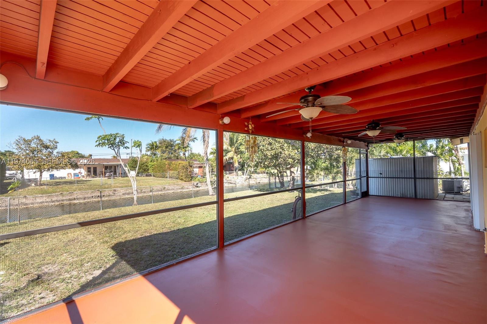 A covered, screened-in patio features a painted concrete floor and exposed orange wooden ceiling beams — 4600 SW 104th Ave, Miami FL 33165, MIAMI, FL