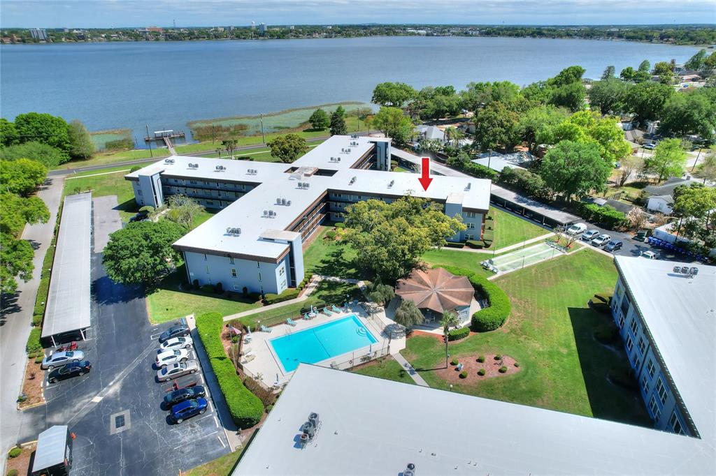 An aerial view shows a multi-story apartment complex with a swimming pool and lakefront access — 333 LAKE HOWARD DRIVE NW UNIT 203C, WINTER HAVEN, FL