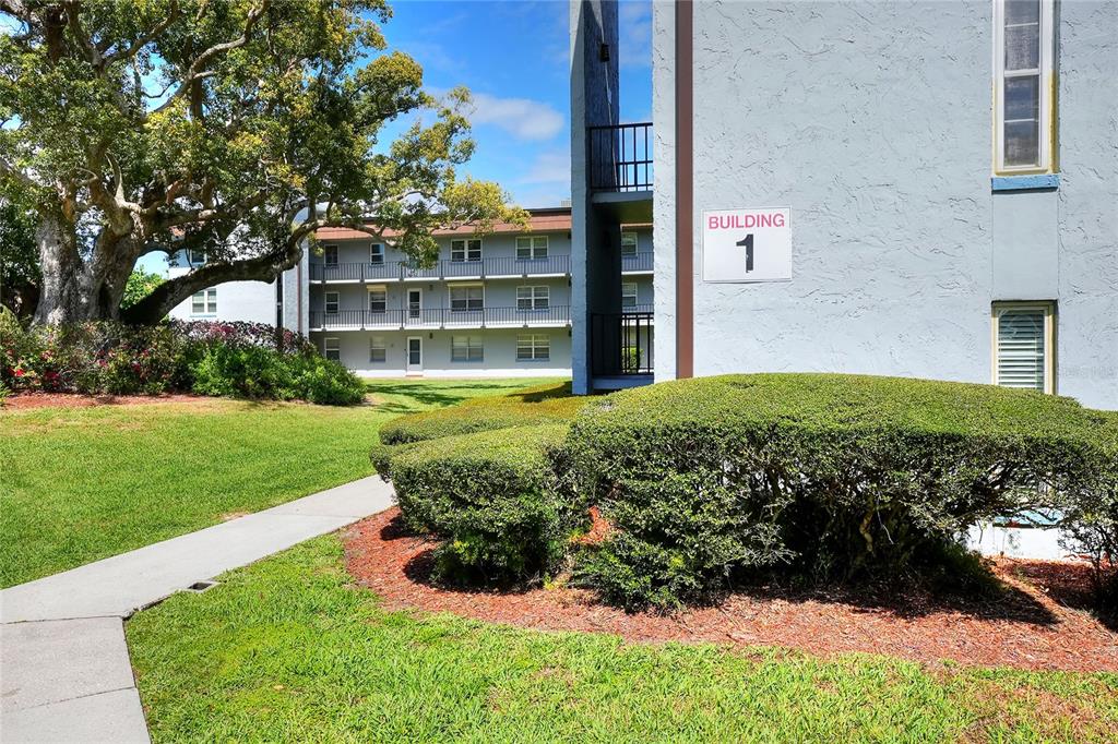 A view of a multi-story apartment building exterior with a sidewalk and landscaped lawn — 333 LAKE HOWARD DRIVE NW UNIT 203C, WINTER HAVEN, FL