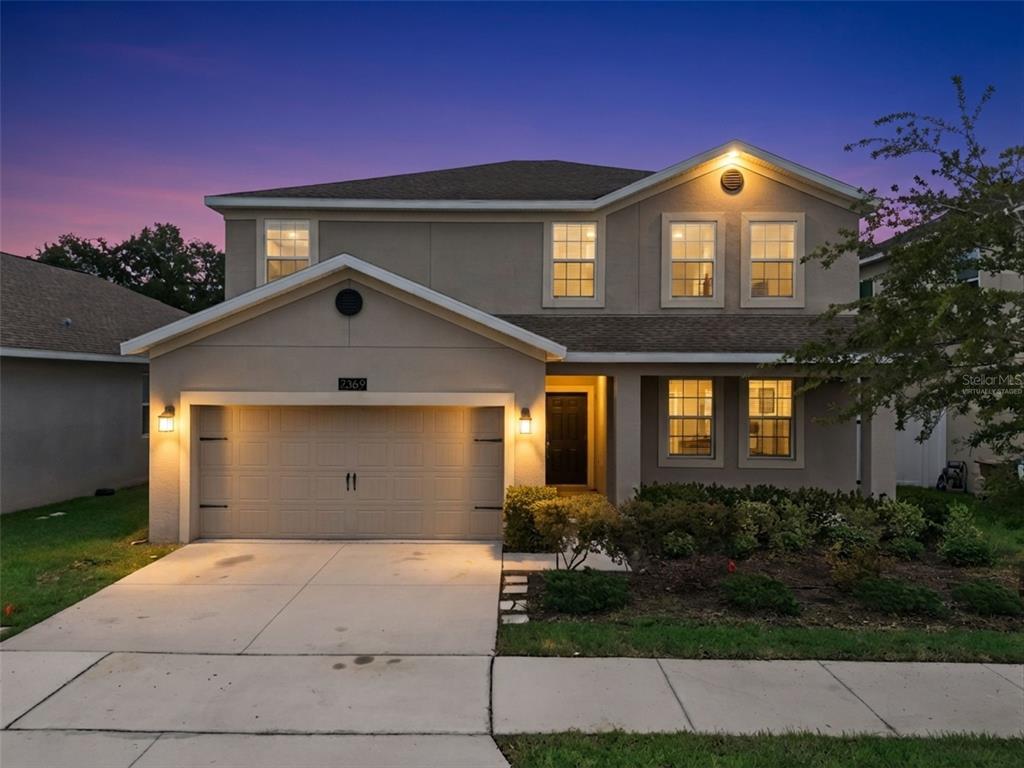 A two-story suburban house with a beige stucco exterior and an attached two-car garage — 2369 CRESCENT MOON STREET, KISSIMMEE, FL