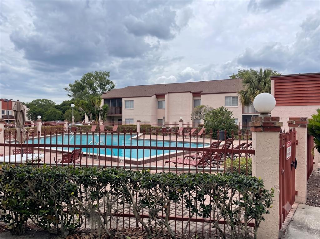 A swimming pool is enclosed by a metal fence in front of a two-story apartment building — 4322 LAKEWAY DRIVE UNIT 13F, ORLANDO, FL