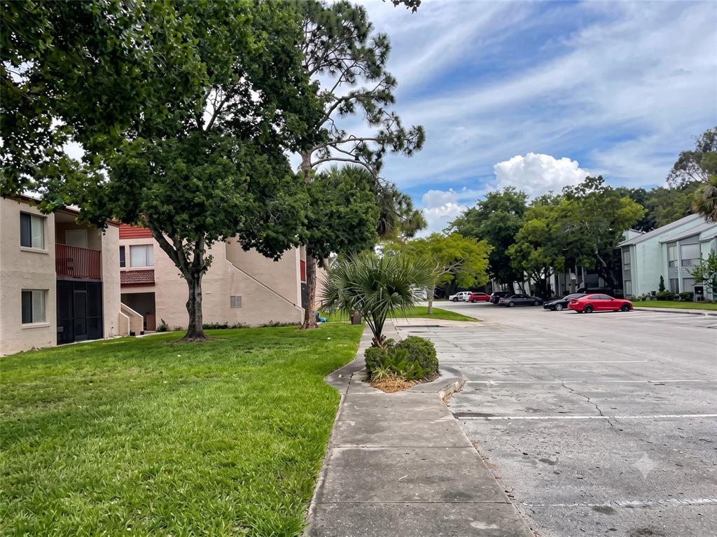 A concrete sidewalk runs alongside a grassy lawn and a parking lot near apartment buildings — 4322 LAKEWAY DRIVE UNIT 13F, ORLANDO, FL