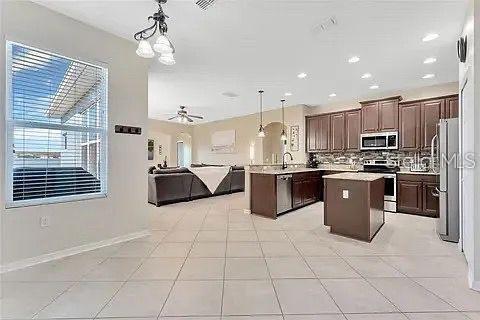 An open-concept kitchen and living area featuring tile floors, dark wood cabinets, and a kitchen island — 589 BLUE CYPRESS DRIVE, GROVELAND, FL