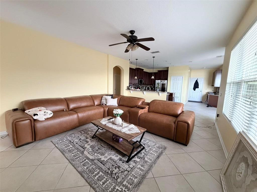 A living room features a large brown leather sectional, a coffee table, and tile flooring — 589 BLUE CYPRESS DRIVE, GROVELAND, FL