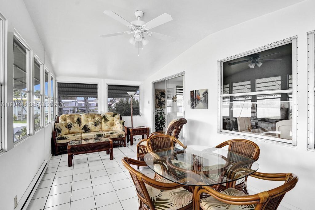 A sunroom features white tile floors, a rattan sofa set, and a glass dining table — 3495 Tee Terrace, Pompano Beach FL 33069, POMPANO BEACH, FL
