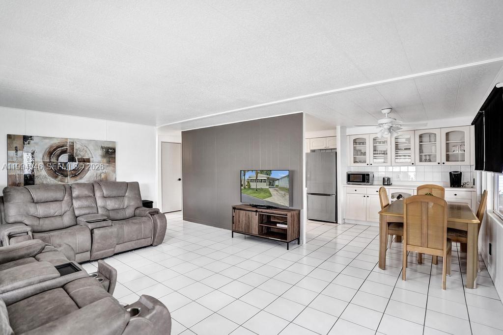 A living room and dining area with white tile floors, gray walls, and white cabinetry — 3495 Tee Terrace, Pompano Beach FL 33069, POMPANO BEACH, FL