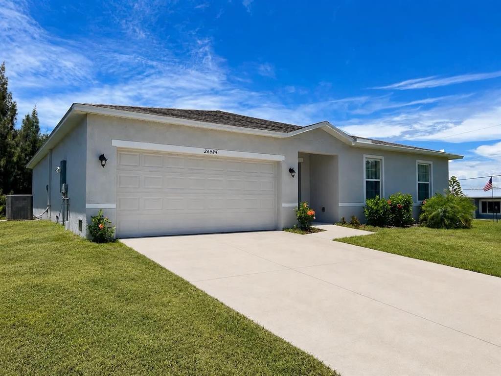 A single-story house with a light-colored exterior, a two-car garage, and a concrete driveway — 26484 VIEW DRIVE, PUNTA GORDA, FL