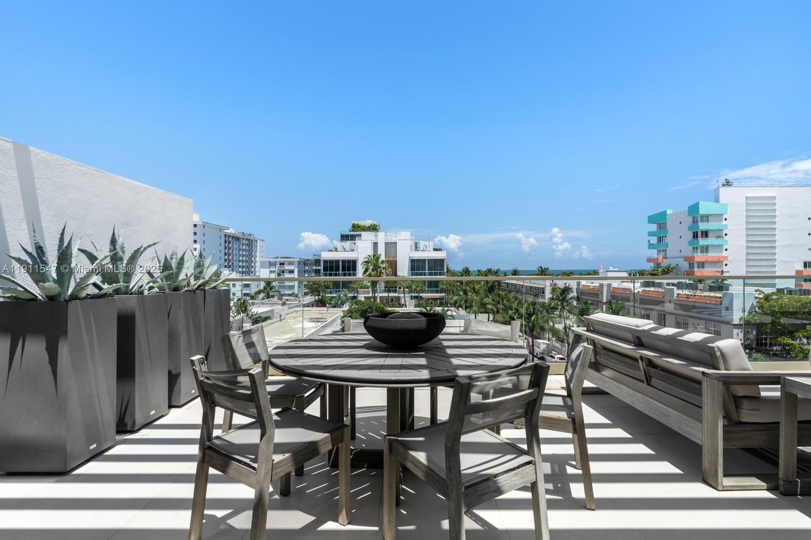 A sunny outdoor terrace features a round dining table, chairs, and potted agave plants — 300 Collins Ave, Miami Beach FL 33139, MIAMI BEACH, FL