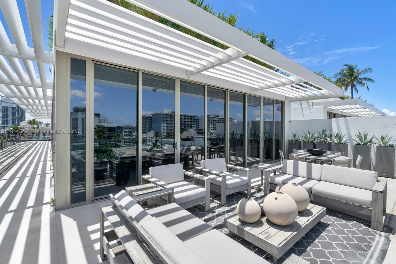 A modern outdoor terrace features white lounge furniture, a slatted pergola, and large glass doors — 300 Collins Ave, Miami Beach FL 33139, MIAMI BEACH, FL