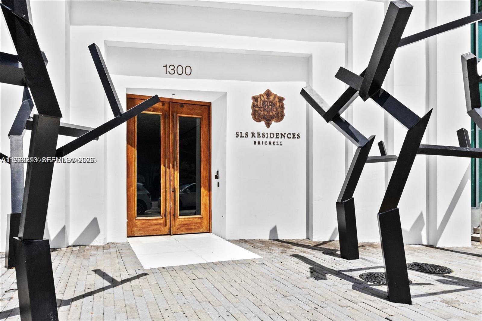 The entrance to a building features wooden double doors and abstract black metal sculptures — 1300 S Miami Ave # 2308, Miami FL 33130, MIAMI, FL