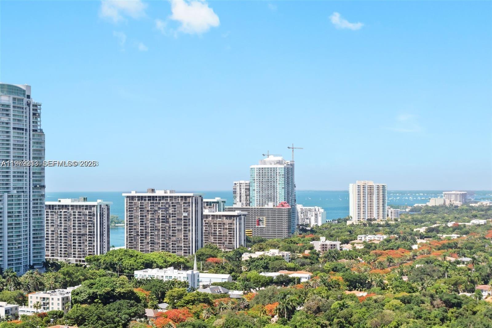 An elevated view of a coastal city skyline featuring high-rise buildings and lush greenery — 1300 S Miami Ave # 2308, Miami FL 33130, MIAMI, FL