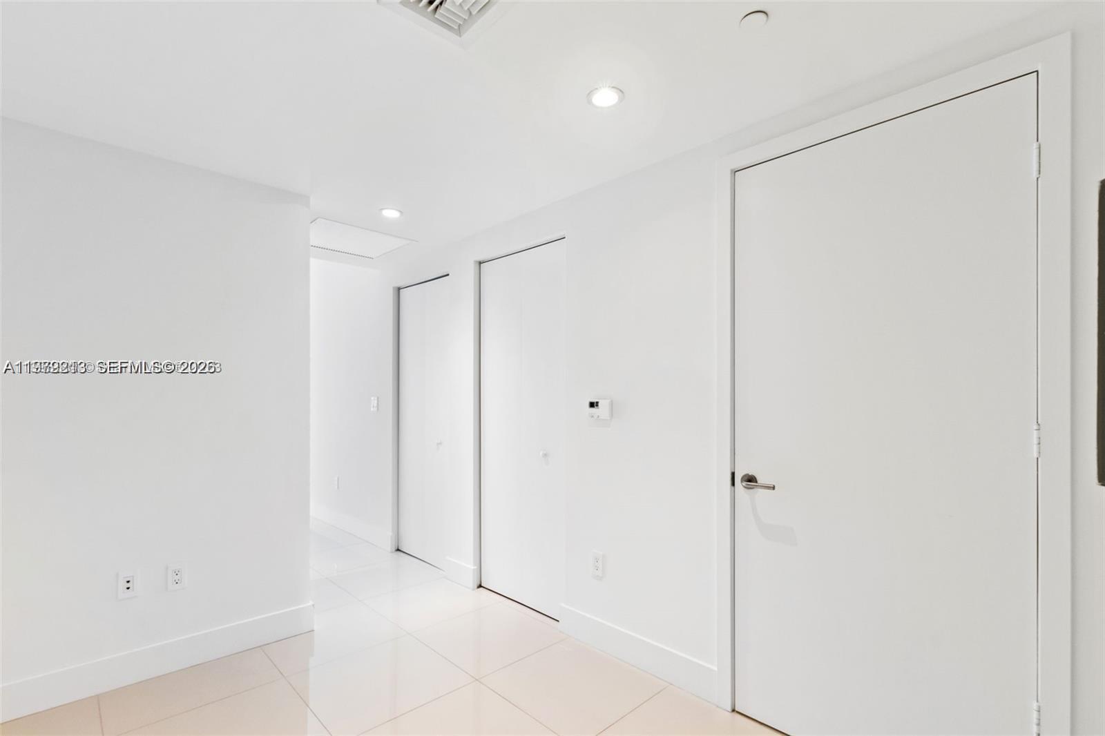 A bright hallway features white walls, tiled floors, recessed lighting, and several closed doors — 1300 S Miami Ave # 2308, Miami FL 33130, MIAMI, FL