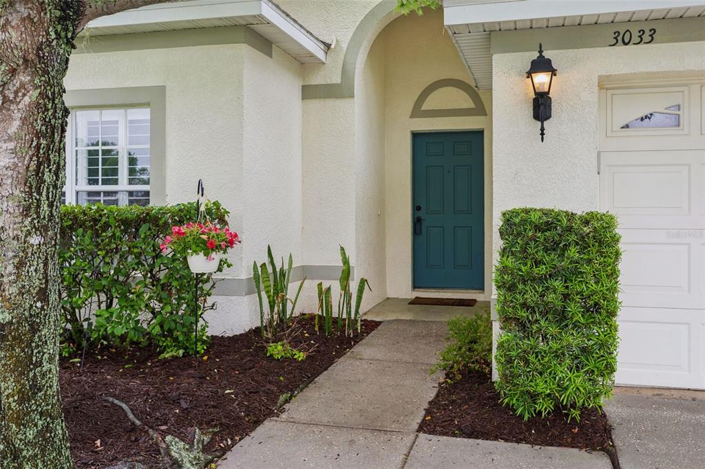 A teal front door sits under an arched entryway next to a white garage door — 3033 GEM LUSTER COURT, VALRICO, FL