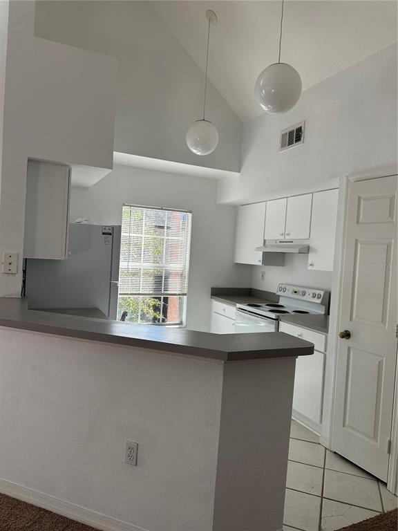 A kitchen features white cabinets, a gray countertop, a breakfast bar, and two pendant lights — 10444 WHITE LAKE COURT UNIT 10444, TAMPA, FL