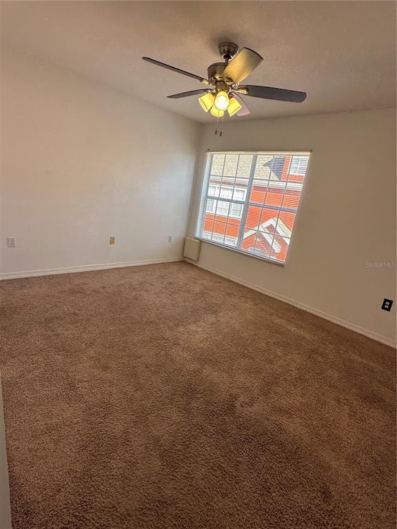 An empty bedroom features tan carpet, beige walls, a ceiling fan, and a single window — 10444 WHITE LAKE COURT UNIT 10444, TAMPA, FL