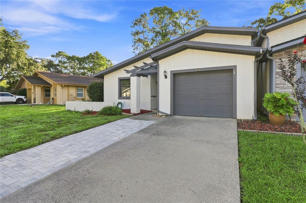 A single-story house with a gray garage door, white stucco walls, and a paved walkway — 83 GOLFVIEW DRIVE, HOMOSASSA, FL