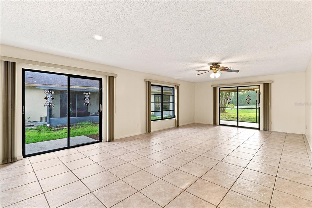 A spacious room with beige tile flooring, a ceiling fan, and multiple sliding glass doors — 83 GOLFVIEW DRIVE, HOMOSASSA, FL