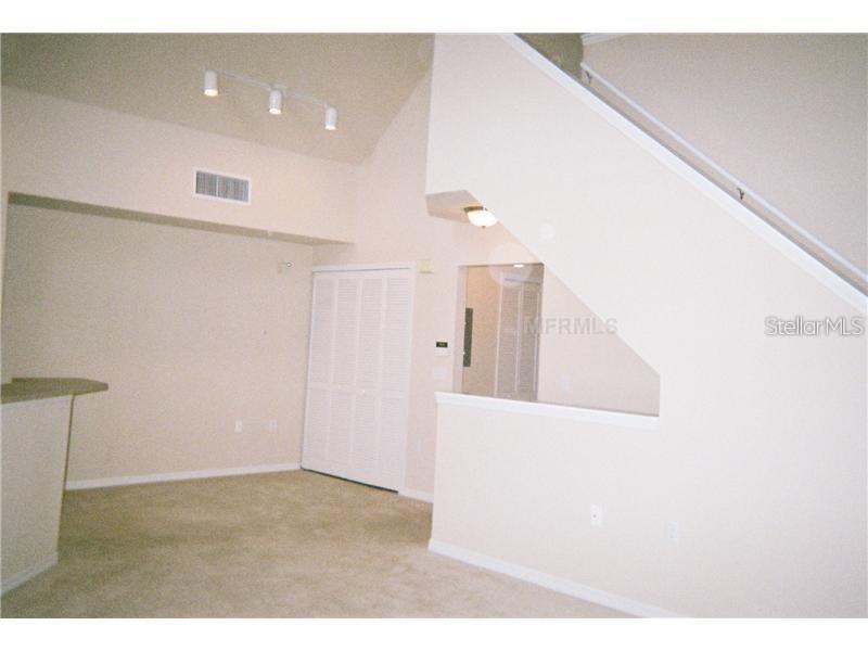 A carpeted room features a staircase with a white railing and a closet with bifold doors — 5581 ROSEHILL ROAD UNIT # 203, SARASOTA, FL