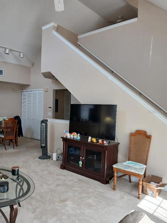 A living room features a television on a dark wood stand beneath a staircase — 5581 ROSEHILL ROAD UNIT # 203, SARASOTA, FL