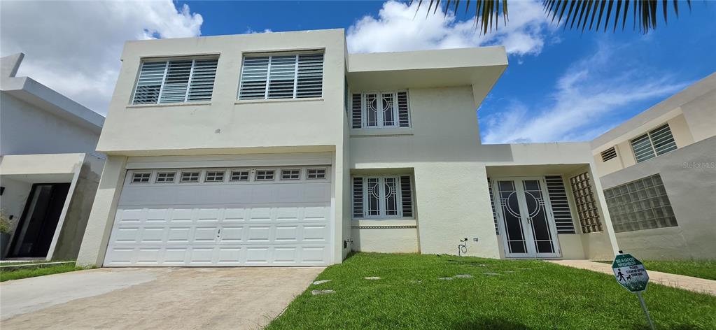 A two-story, light-colored house with a two-car garage and a front lawn — ST 1 ESTANCIAS DE SAN FERNANDO, CAROLINA, PR