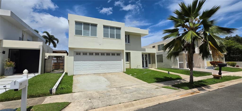 A two-story house with a white exterior, a two-car garage, and a palm tree — ST 1 ESTANCIAS DE SAN FERNANDO, CAROLINA, PR
