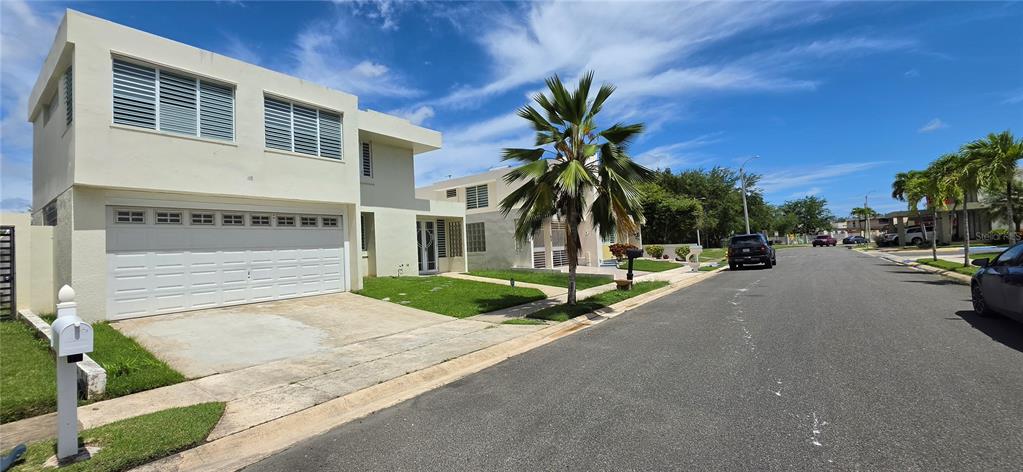A two-story house with a white garage and louvered windows sits on a suburban street — ST 1 ESTANCIAS DE SAN FERNANDO, CAROLINA, PR