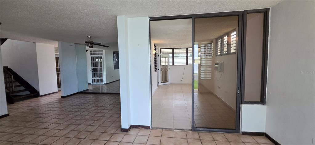 An interior view shows a tiled living area, a staircase, and a glass-enclosed sunroom — ST 1 ESTANCIAS DE SAN FERNANDO, CAROLINA, PR