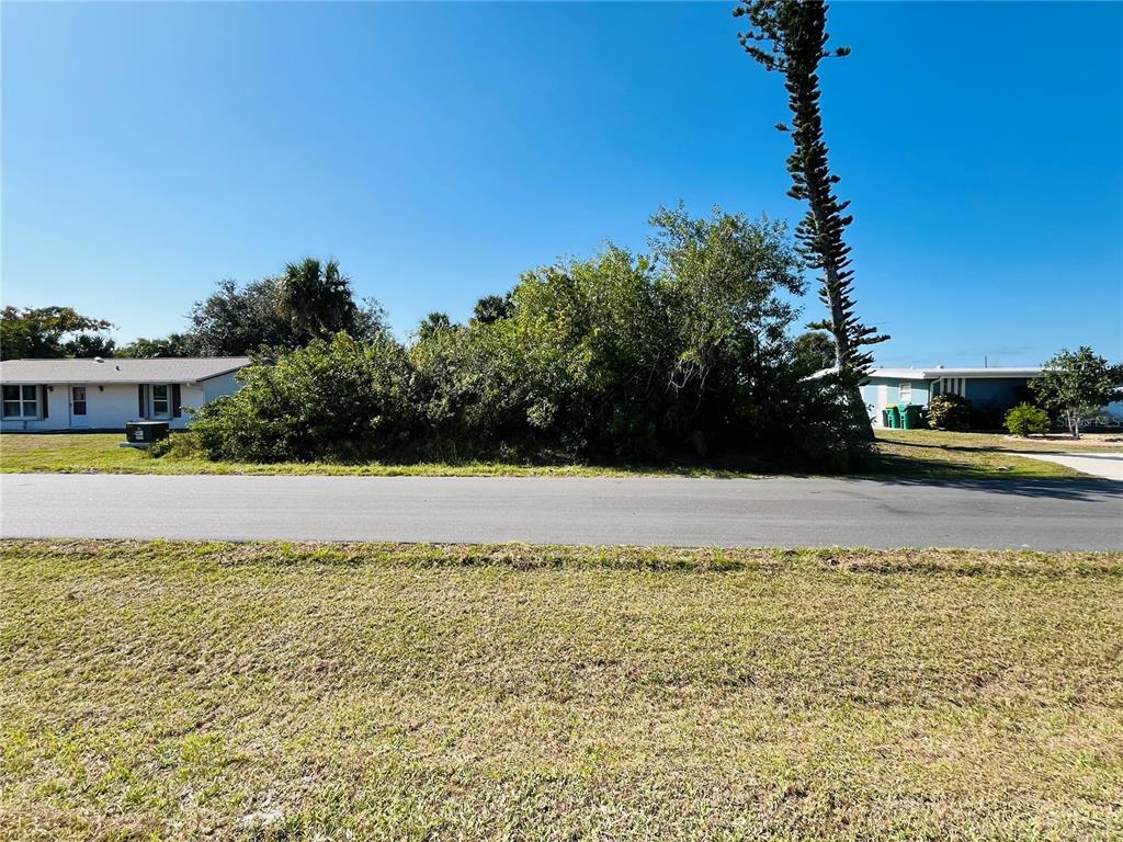 A vacant, overgrown lot sits between two residential houses along a paved street — 4231 ONEILL STREET, PORT CHARLOTTE, FL