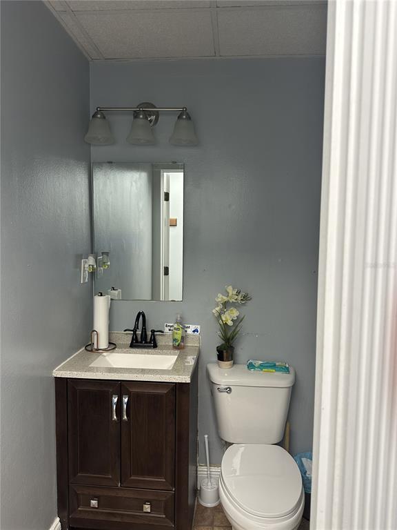 A small bathroom features a dark wood vanity, a white toilet, and a wall mirror — 318 N JOHN YOUNG PARKWAY UNIT 101, KISSIMMEE, FL