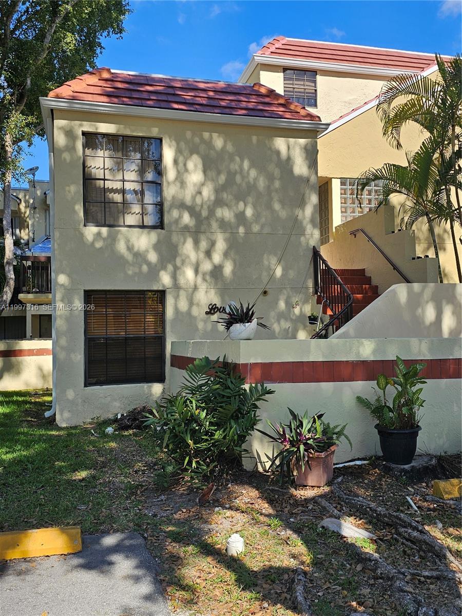 A two-story stucco building features a red tile roof, exterior staircase, and ground-level landscaping — 13063 SW 88th Ter S # B, Miami FL 33186, MIAMI, FL