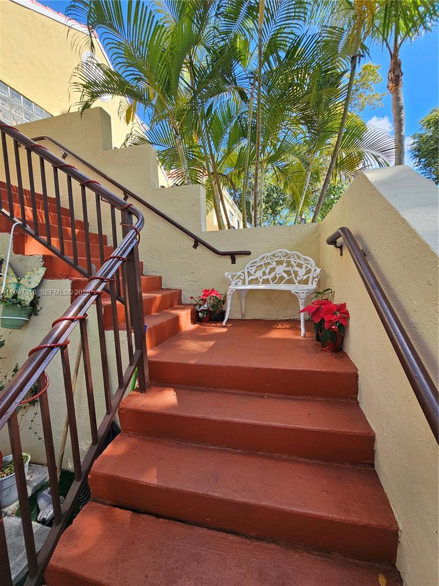 An outdoor staircase with terracotta-colored steps features a white metal bench and potted poinsettias — 13063 SW 88th Ter S # B, Miami FL 33186, MIAMI, FL