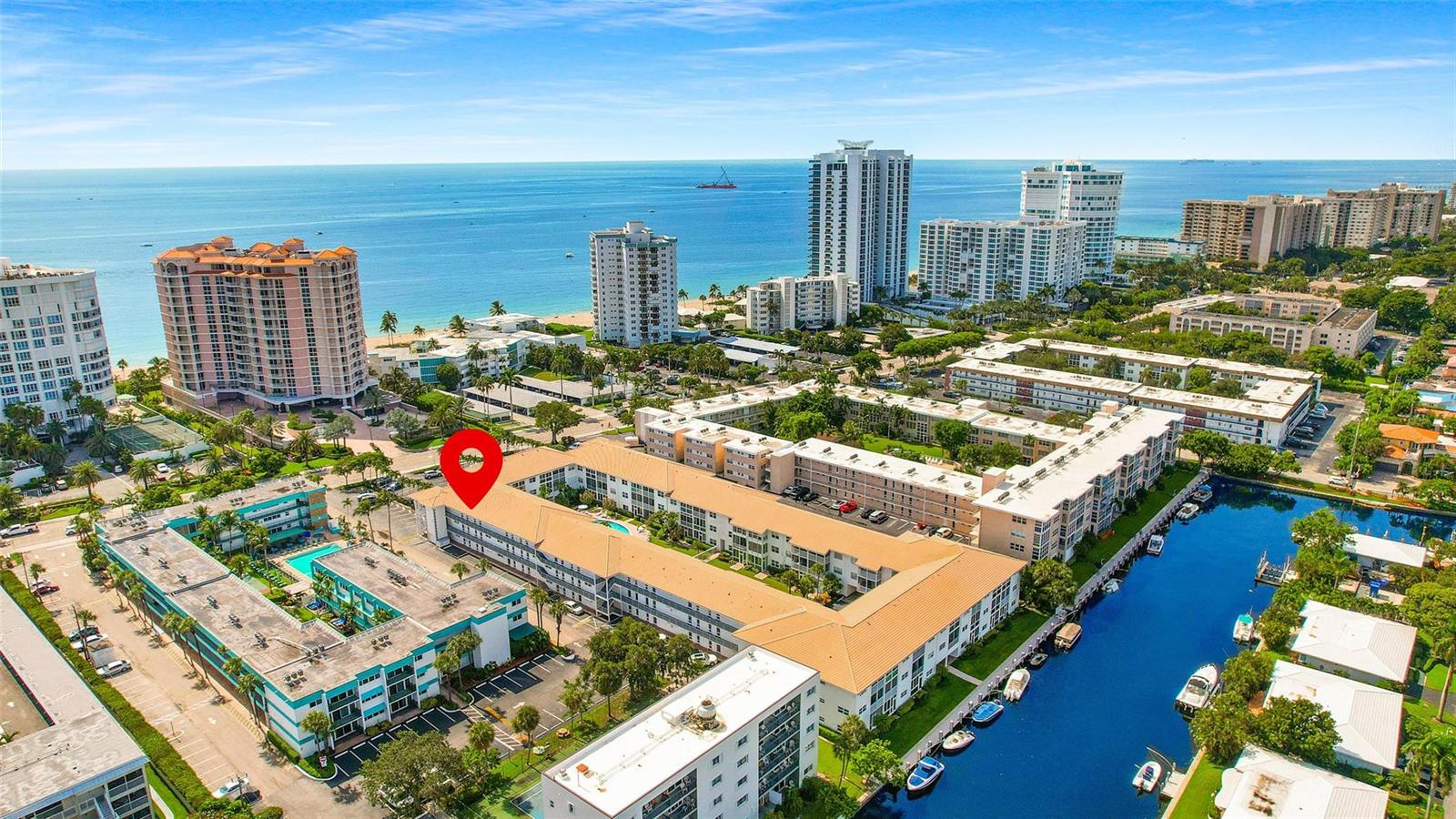 An aerial view shows a multi-story apartment complex near a canal and the ocean — 1461 S Ocean Boulevard # 329, Pompano Beach FL 33062, POMPANO BEACH, FL