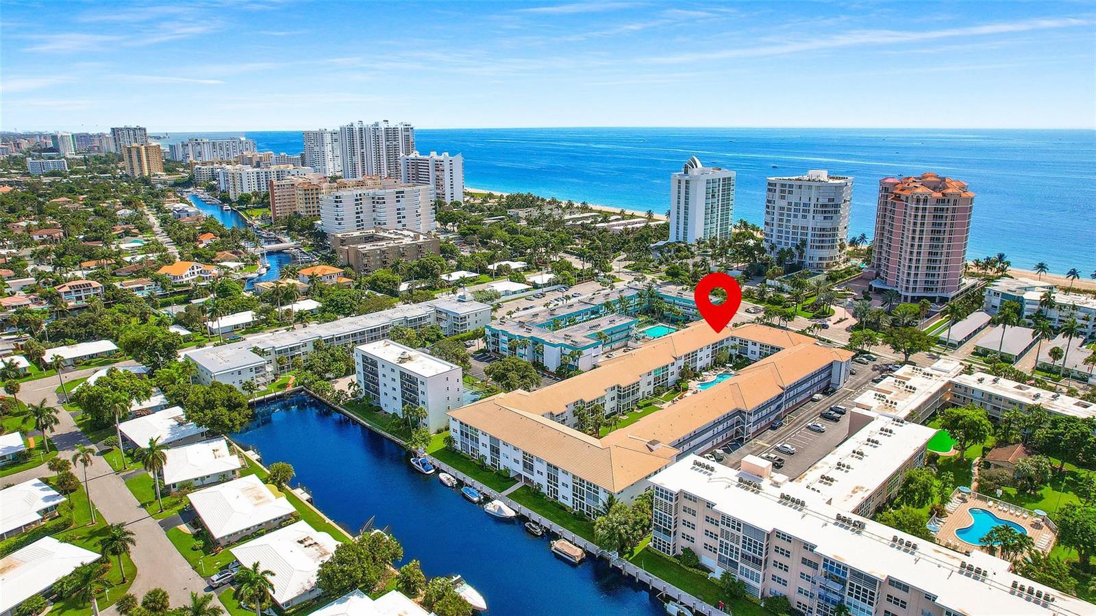 Aerial view of a multi-story apartment complex with a pool, canal, and oceanfront buildings — 1461 S Ocean Boulevard # 329, Pompano Beach FL 33062, POMPANO BEACH, FL