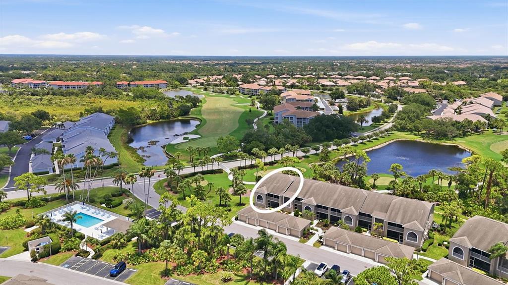 An aerial view shows a multi-story residential building with a circled unit near a pond — 9540 HIGH GATE DRIVE UNIT 1411, SARASOTA, FL