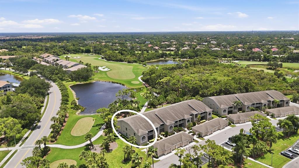 An aerial view shows a multi-story condominium building surrounded by a golf course and pond — 9540 HIGH GATE DRIVE UNIT 1411, SARASOTA, FL