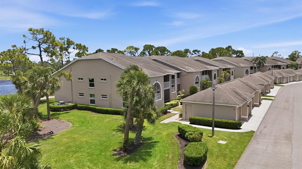 An aerial view shows a multi-story apartment building with tan siding and attached garages — 9540 HIGH GATE DRIVE UNIT 1411, SARASOTA, FL