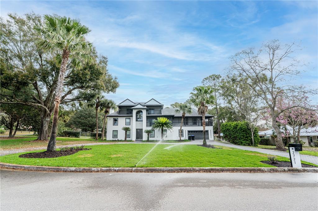A two-story white house with a dark roof sits behind a green lawn — 2721 INGEBORG COURT, WINDERMERE, FL