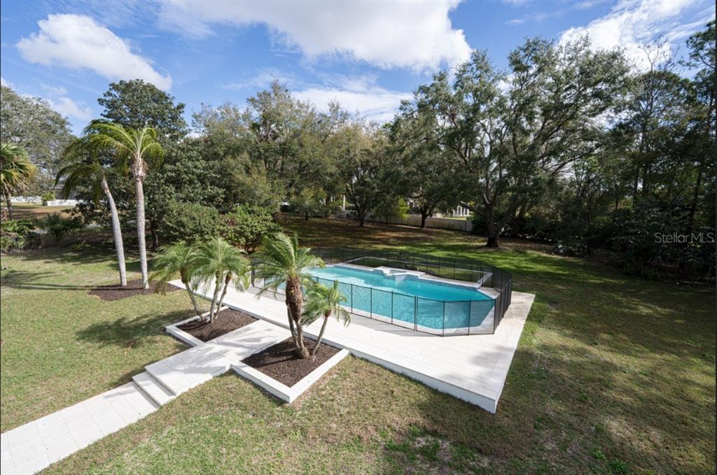 An aerial view of a backyard featuring a swimming pool enclosed by a black safety fence — 2721 INGEBORG COURT, WINDERMERE, FL