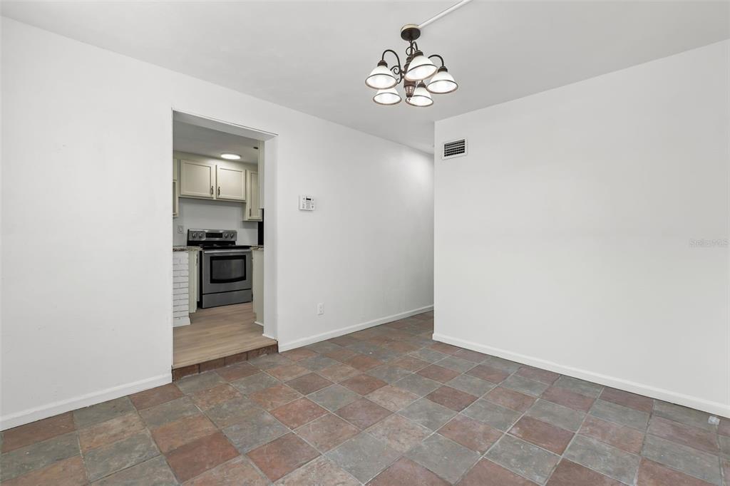 A dining area with tile flooring and a chandelier leads into a kitchen — 1432 RICHMOND AVENUE, DAYTONA BEACH, FL