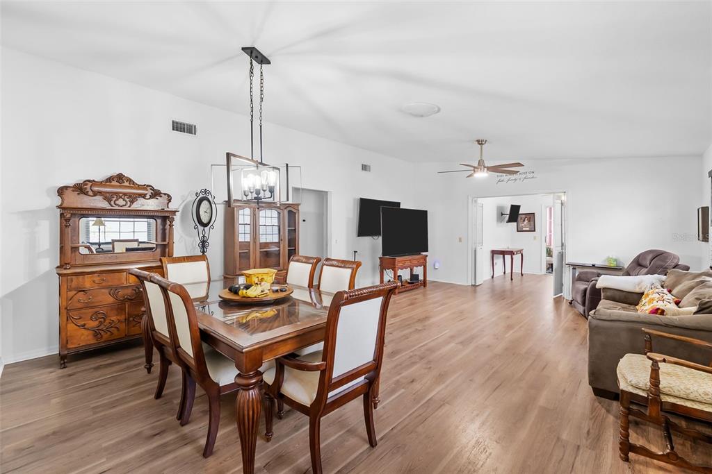 A dining area with a wood table and chairs flows into a living room space — 37420 TEABERRY LOOP, ZEPHYRHILLS, FL