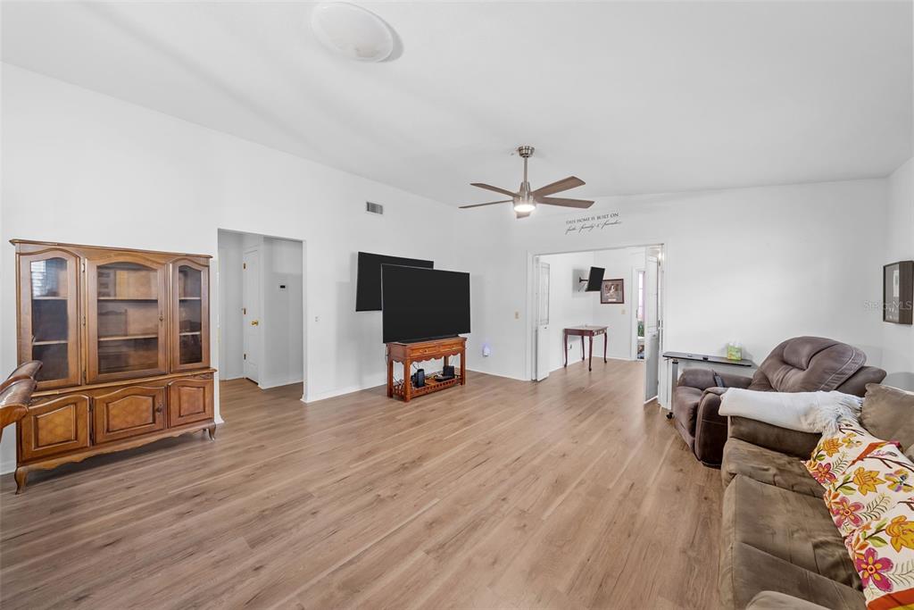A living room with wood-look flooring, a ceiling fan, a wooden hutch, and a television — 37420 TEABERRY LOOP, ZEPHYRHILLS, FL